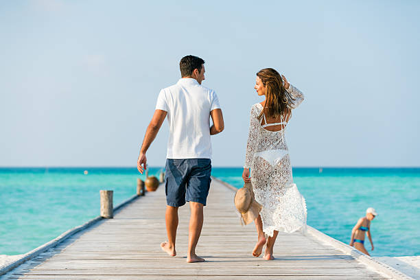 Young couple walking along jetty at Dhiffushi Holiday island, South Ari atoll, Maldives. Model and Property released. Hi resolution photo.