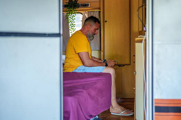 istock Mature adult man relaxing inside camper van using smartphone 2246483882