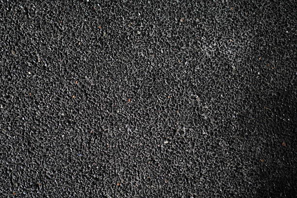 Close-up shot showing the detailed texture of a dark asphalt road surface, suitable for construction or material related contexts.