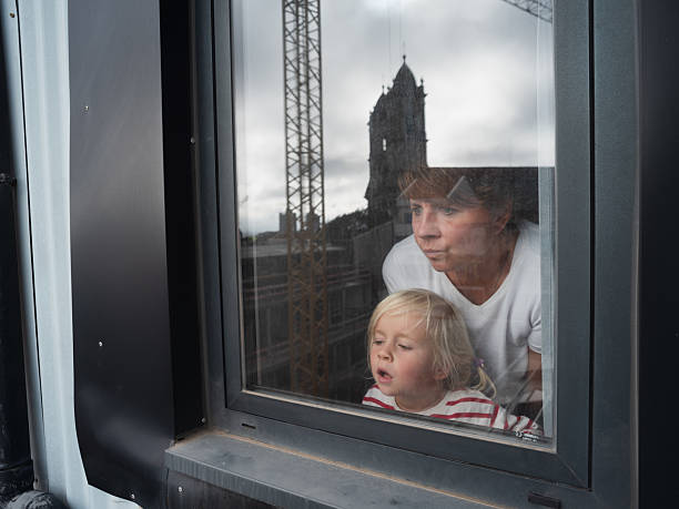 Young mother with her child looking outside checking the weather is it raining . High quality photo