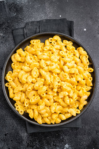 istock Golden mac and cheese in a black skillet, rustic dark background, fork beside 2246489861