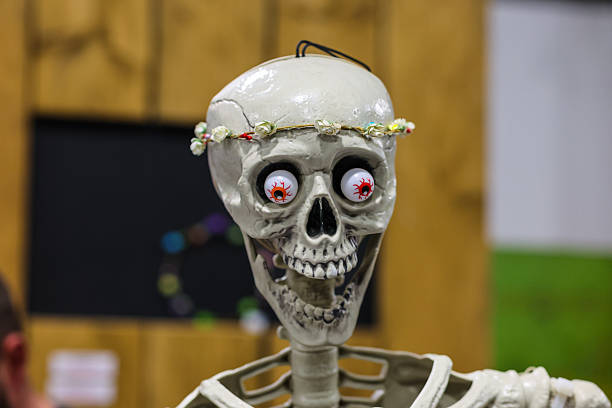 A humorous close-up of a decorative skeleton featuring googly eyes and a small floral crown. This playful image combines spooky and comedic elements, making it perfect for n Halloween themes, quirky humor, or creative art concepts.