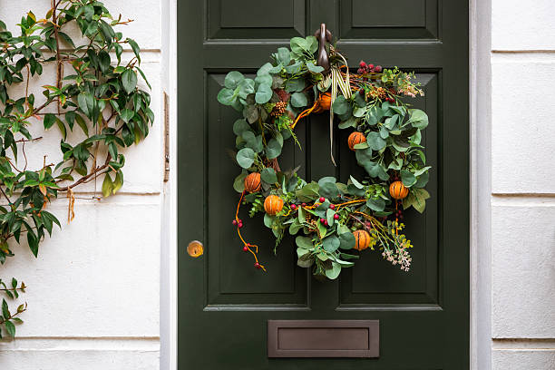 An autumnal Halloween wreath on a green front door in the city.