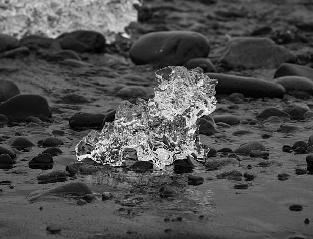 block of ice on black and volcanic sand
