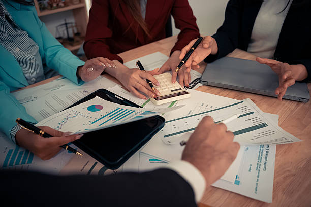 istock Businessman and team analyzing statistics with documents and graphs. Accounting consultant dealing with data, budget and profit chart for company. Close up. 2246495658