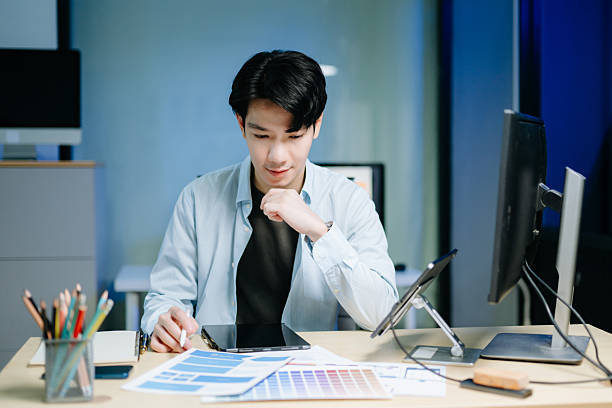 istock Asian male designer pointing at UX wireframes on screen and tablet in modern office. Ideal for themes in UI UX, digital product design, software 2246498006