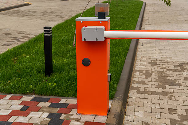 istock A bright orange security barrier controls access to a parking lot surrounded by green grass and pavement on a sunny day 2246498358
