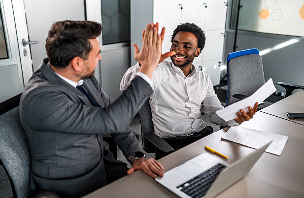 istock Businessmen celebrating success with high five in office 2246504218