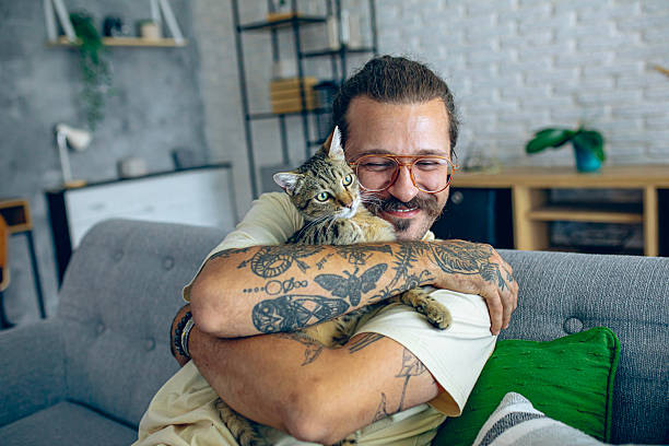 istock Relaxed man sitting on the sofa at home while gently petting his cat 2246509441