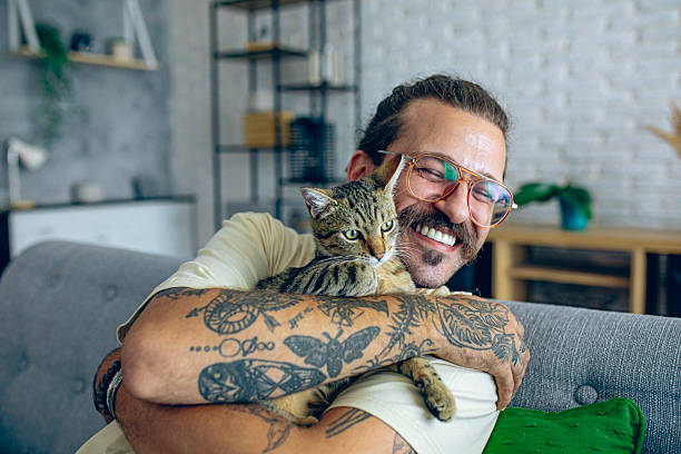 istock Relaxed man sitting on the sofa at home while gently petting his cat 2246509462