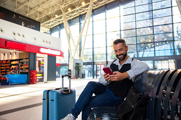 istock Man looking at phone while waiting for boarding pass on airplane 2246509702