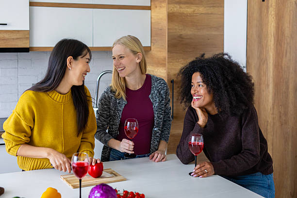 istock Three women enjoy preparing food and sharing wine in a bright modern kitchen, laughing and talking in a warm, relaxed atmosphere 2246510131