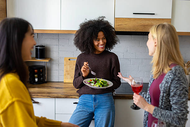 istock Three cheerful women enjoy fresh salad and lively conversation while laughing and relaxing together in a cozy kitchen 2246510411