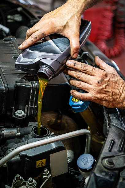 istock Mechanic pouring engine oil during car maintenance service 2246510497