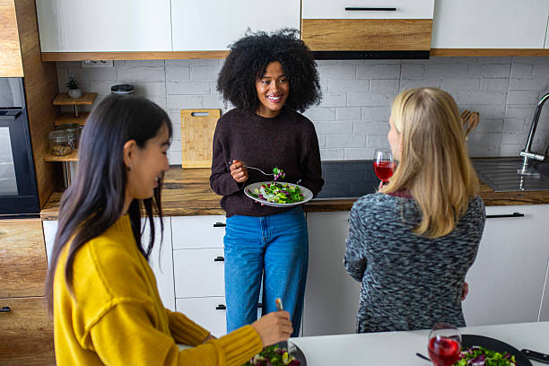 istock Three cheerful women enjoy fresh salad and lively conversation while laughing and relaxing together in a cozy kitchen 2246510753
