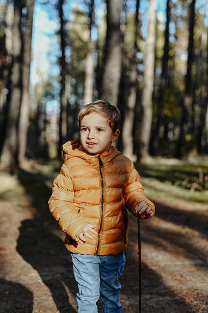 istock Young Boy In Orange Puffer Jacket Exploring A Forest Trail On A Sunny Day 2246517783