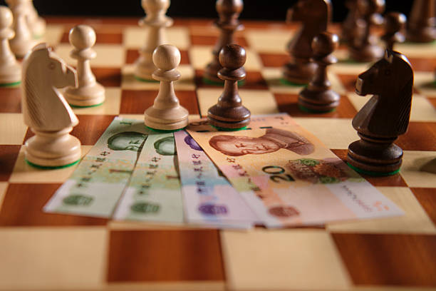 istock Chess pieces on a chessboard with chinese yuan banknotes underneath. Game theory and strategy concept for business finance. 2246518038