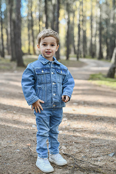 istock Young Boy in Denim Jacket Standing on Forest Path with Branches in Hands 2246518075