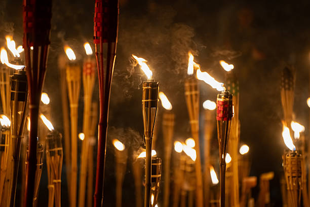 istock Numerous bamboo torches burning closely together in Latvia, producing warm flickering flames and drifting smoke that fill the night scene with layered illumination and a dramatic vertical fire pattern 2246526714