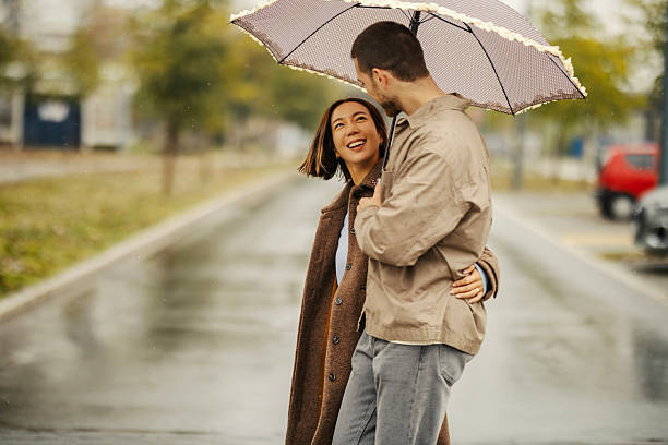 istock Happy couple walking together under umbrella in rain 2246528156