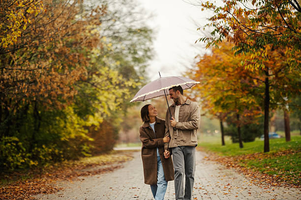 istock Romantic couple walking in autumn park under umbrella 2246528163