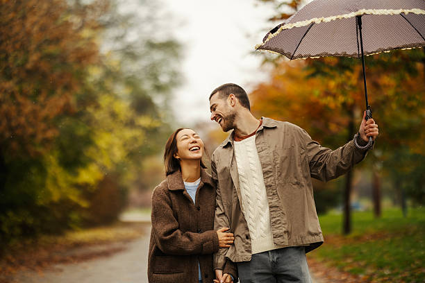 istock Loving couple walking in autumn rain under umbrella 2246528164