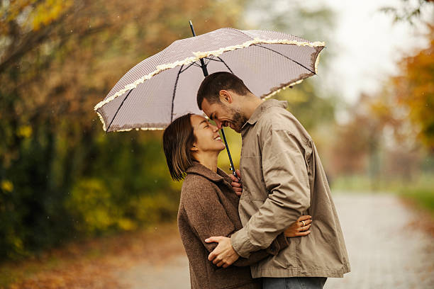 istock Happy couple embracing in rain with umbrella 2246528174