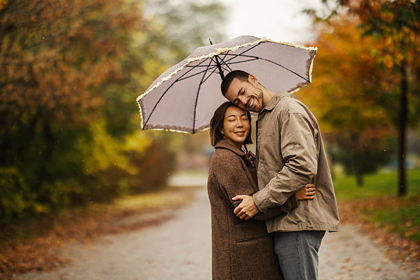 istock Happy couple hugging under umbrella in autumn rain 2246528182
