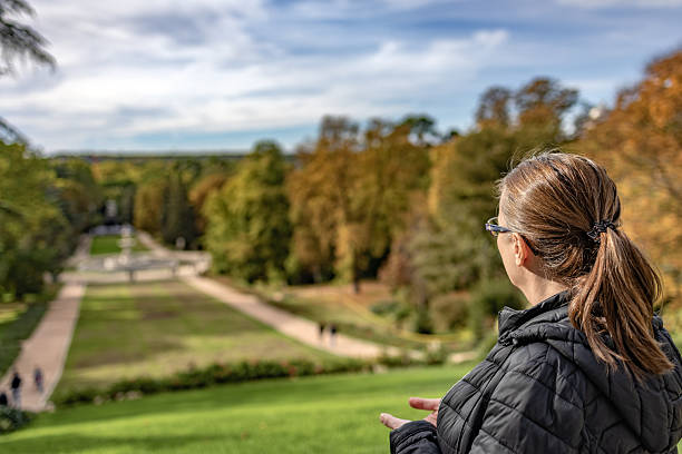 Madrid. Spain. Woman standing with her back to the camera, looking out over a park with trees changing colors during autumn, contemplating the landscape