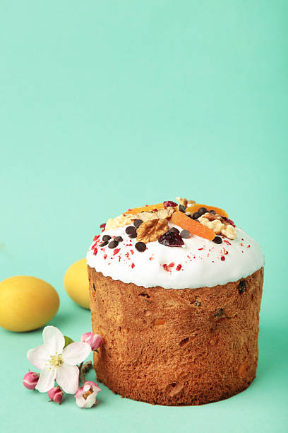 Traditional easter cakes with colorful sprinkles, with eggs and spring flowers on mint background. Vertical photo