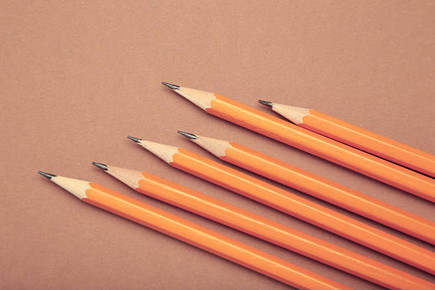 Graphite pencil with eraser on brown background. School stationery. Top view