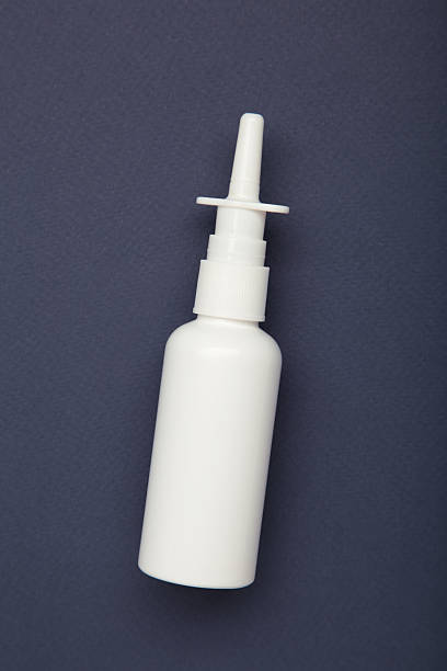 Nasal spray bottle on dark blue background. Top view