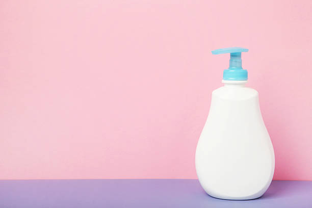 White plastic bottle of liquid soap on pink background. Top view
