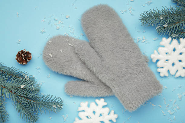 Winter grey mittens with snowflakes on blue background, warm mittens. Top view