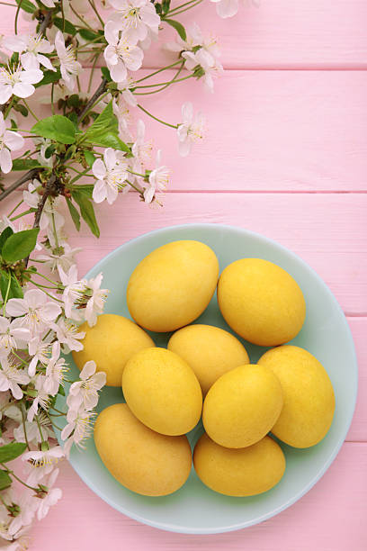 Easter eggs and spring flowers on pink wooden background. Top view