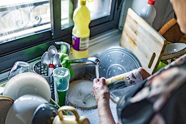 istock Person washing dishes, hands cleaning at kitchen sink 2246529791