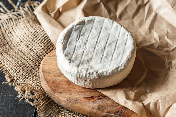 istock Soft cheese on wooden board with rustic paper and texture backdrop at kitchen table 2246529839