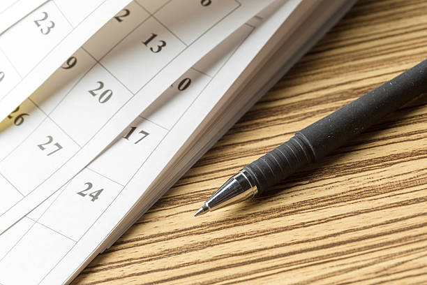 istock Close-up of a pen resting next to a calendar with various dates highlighted 2246529861