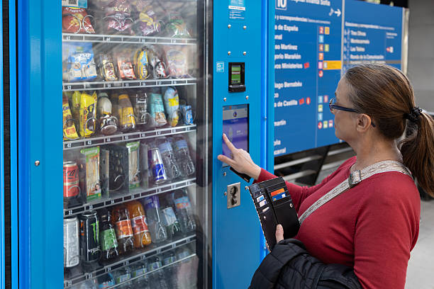 istock Woman buying snacks from modern vending machine 2246530358