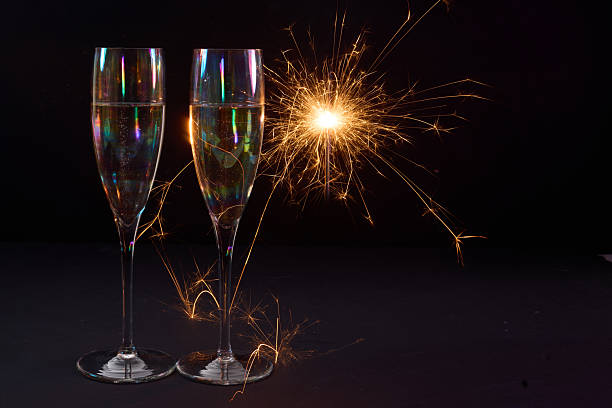 istock Sparkling Celebration. Two champagne glasses with bright sparklers against a dark background 2246530556
