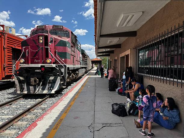 Passengers waiting on platform as a red freight train arrives at Creel station along the Copper Canyon Chepe Express route in Chihuahua, Mexico. Photographed June 17, 2025