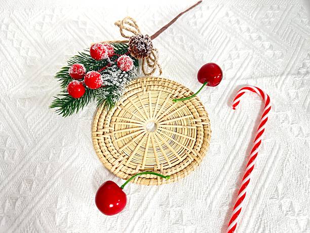 istock Decorative Christmas Arrangement with Cherry Accents on a Textured White Background Featuring a Candy Cane and Evergreen Sprigs 2246535096
