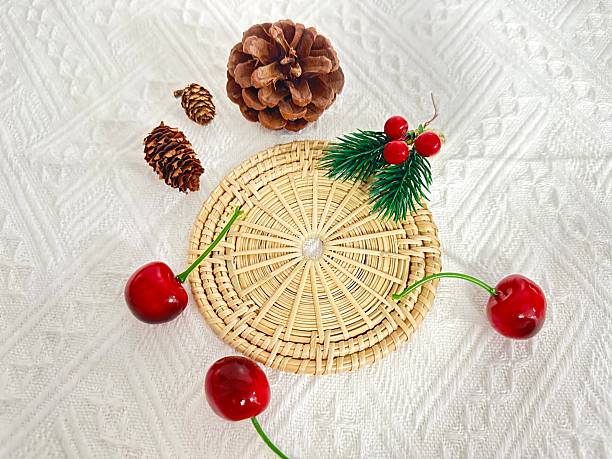 istock Decorative arrangement featuring cherries, pine cones, and greenery on a woven mat, creating a rustic and cozy aesthetic for home decor or seasonal themes 2246535206