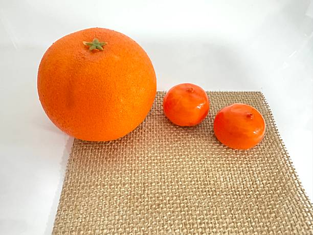 istock Fresh, vibrant orange and two small tangerines on a textured burlap surface, ideal for healthy food concepts, dietary choices, and seasonal fruits. 2246536555