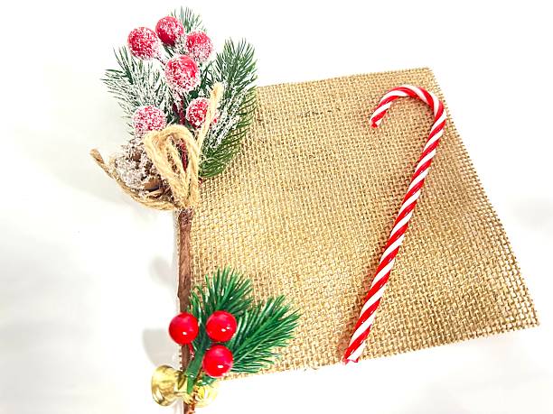 istock Festive Christmas Arrangement with Red Candy Cane, Greenery, and Holiday Decorations on a Rustic Sackcloth Backdrop 2246536659