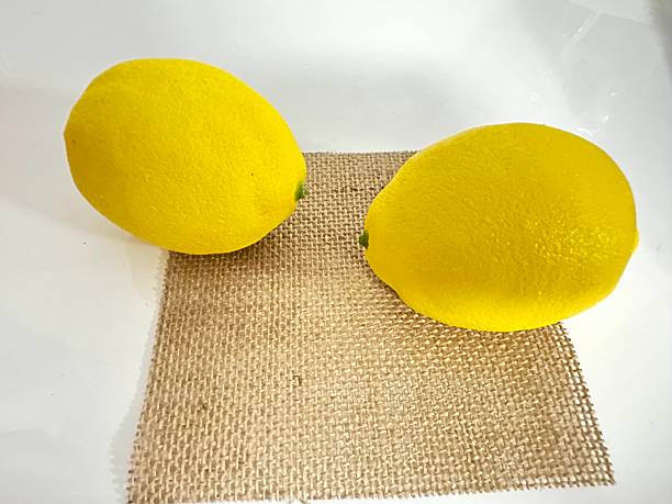 istock Two Bright Yellow Lemons on a Natural Burlap Mat with Clean White Background for Fresh Produce Concept in Food Photography 2246536760