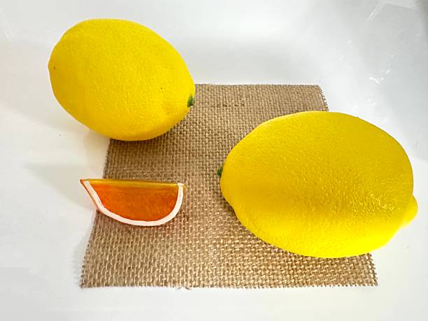 Fresh Bright Lemons and Orange Slice on Natural Burlap Fabric Background for Kitchen or Food Themed Projects
