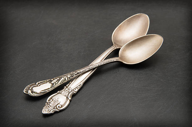 Hand Holding a Metal Spoon on Dark Background