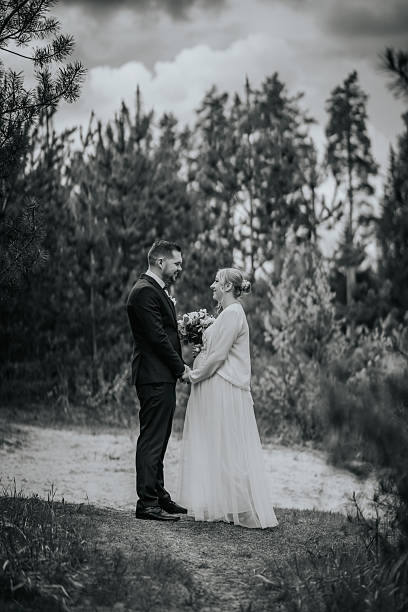 istock Couple in formal attire standing together in a serene forest setting, exchanging vows with a bouquet, capturing the essence of love and commitment in nature's embrace 2246539911