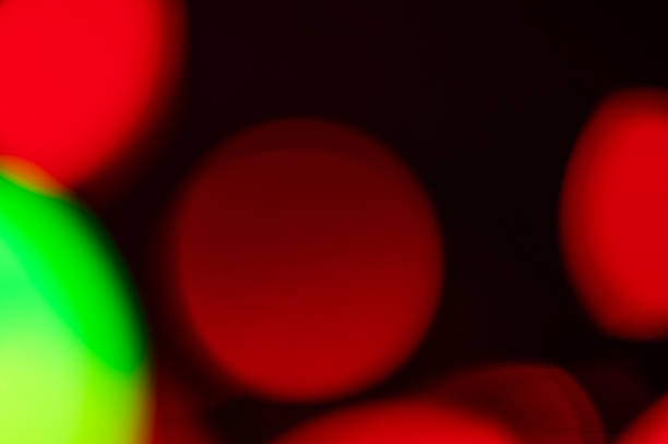 Red and green lights with a bokeh effect on a dark background close up. A festive illumination and decor concept for cards, advertisements or banners with space for text